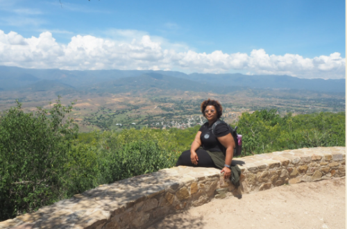 Black woman sitting alone on top of a mountain
